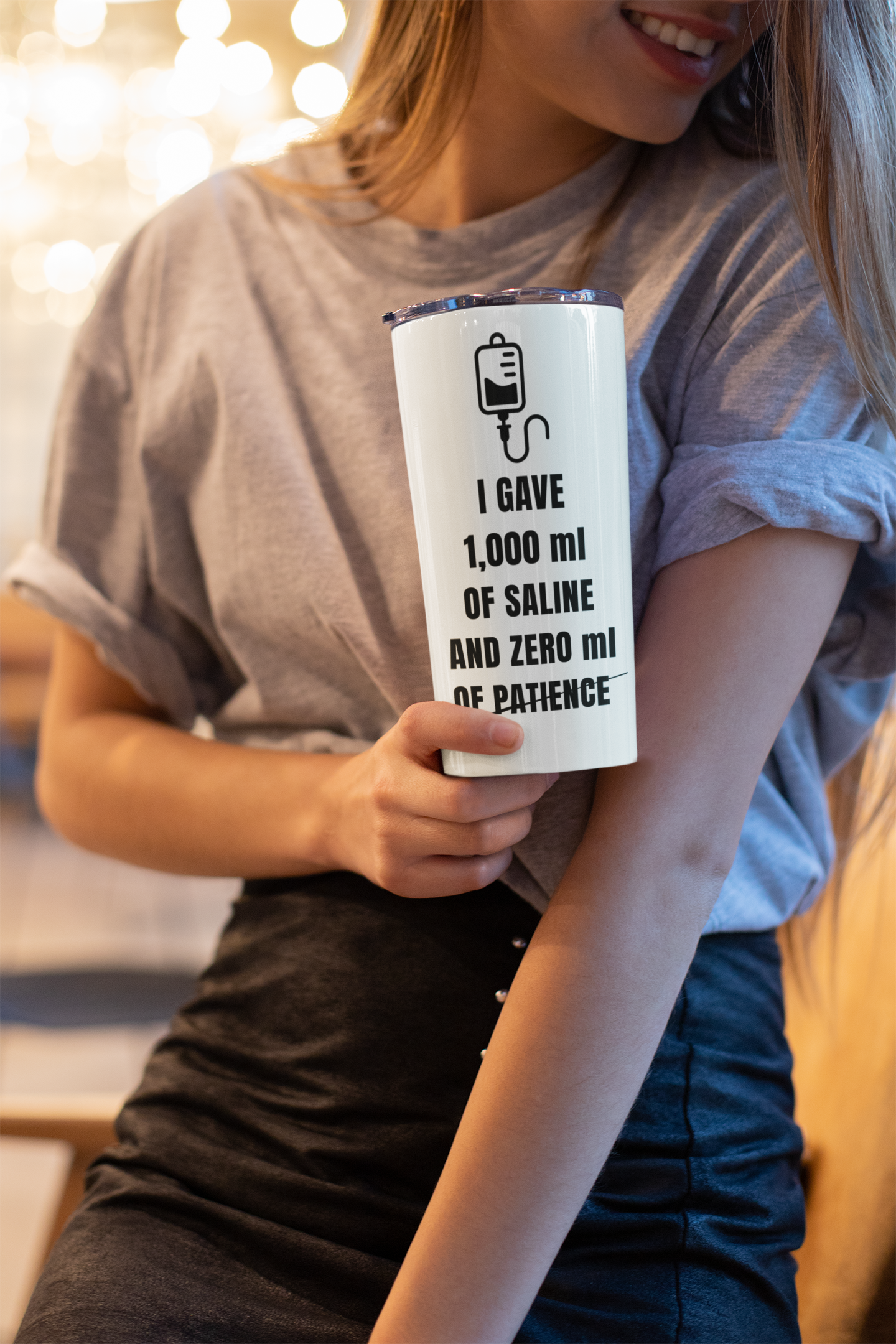 Nurse in streetwear-style scrubs holding white tumbler, photographed from waist-up for lifestyle realism.