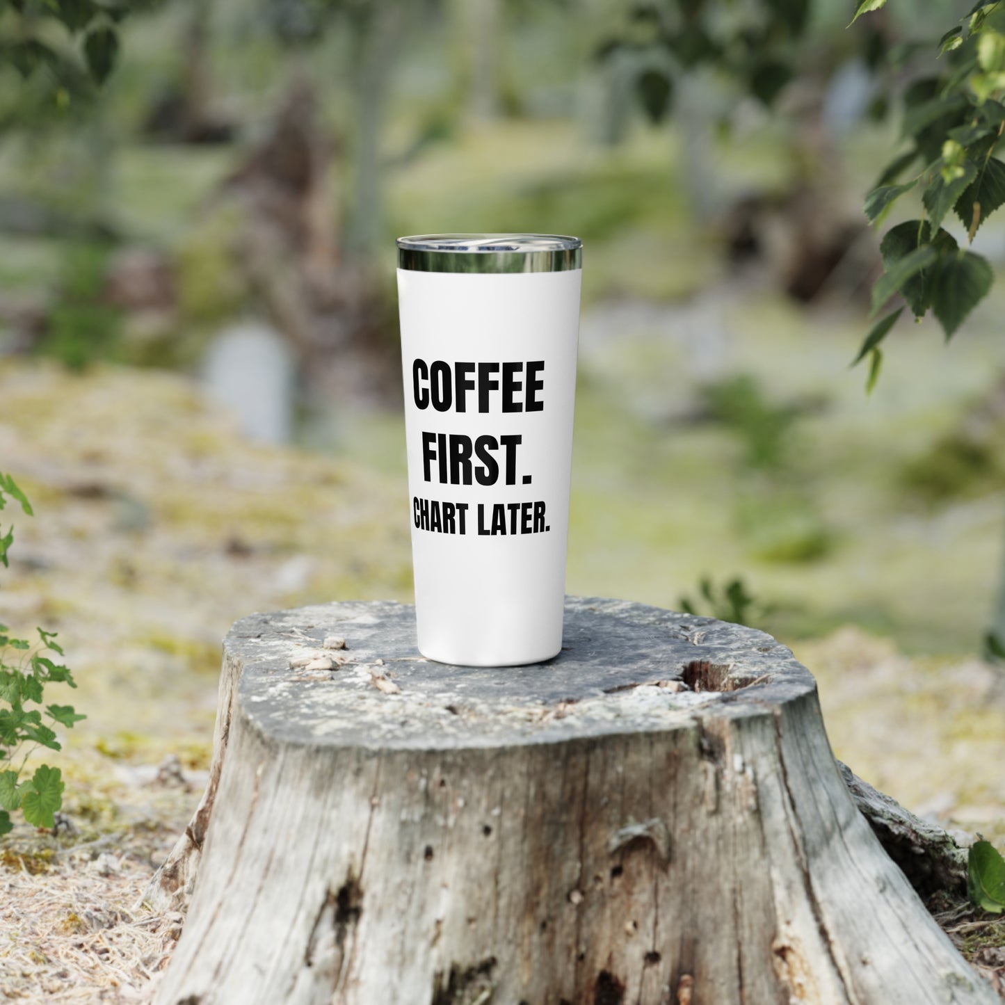 “Coffee First, Chart Later” tumbler on a wooden post during outdoor nurse break.