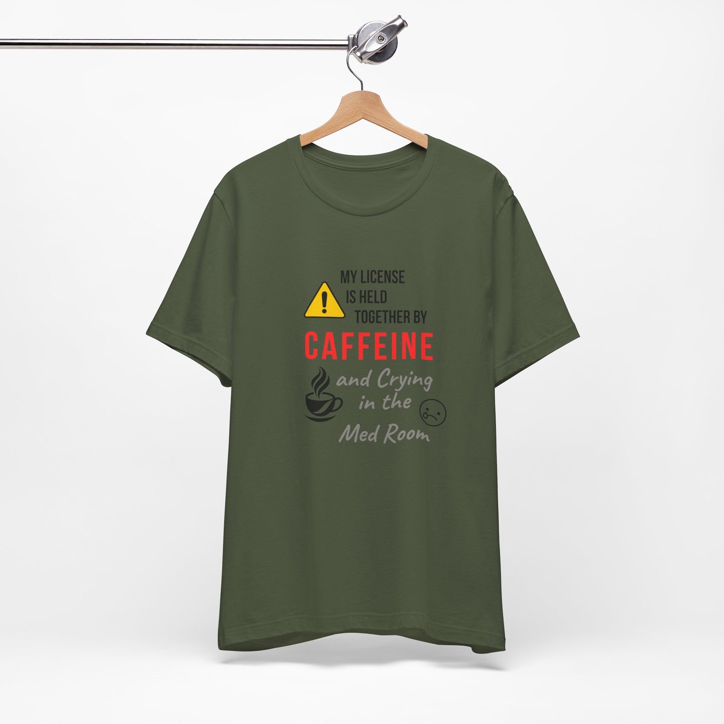 Military green “Held Together by Caffeine” nurse tee on a hanger, perfect for night shift humor.