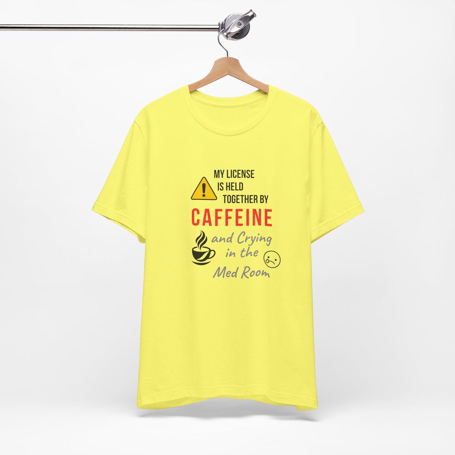 Yellow “Held Together by Caffeine” RN shirt displayed on a hanger, studio lighting.