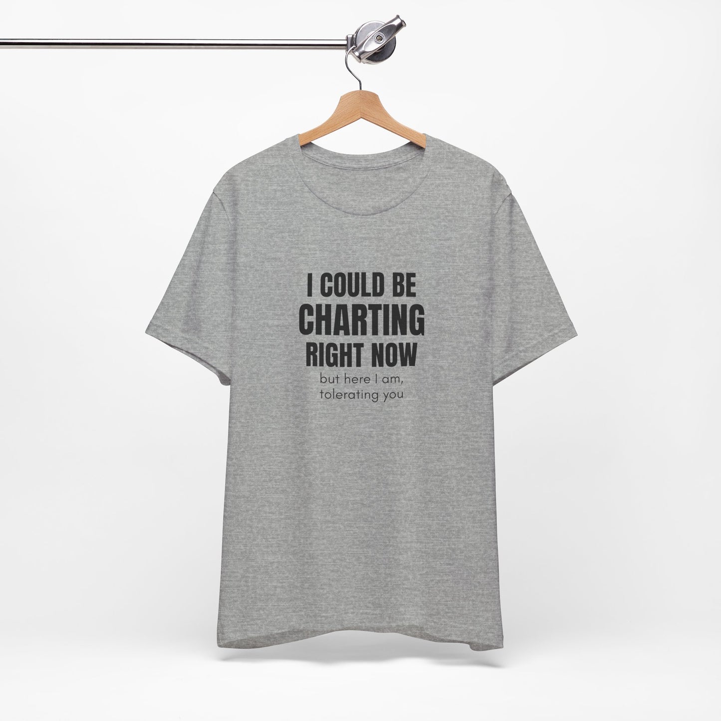 Heather grey “I Could Be Charting Right Now” nurse shirt hanging on wooden hanger, flat lay.