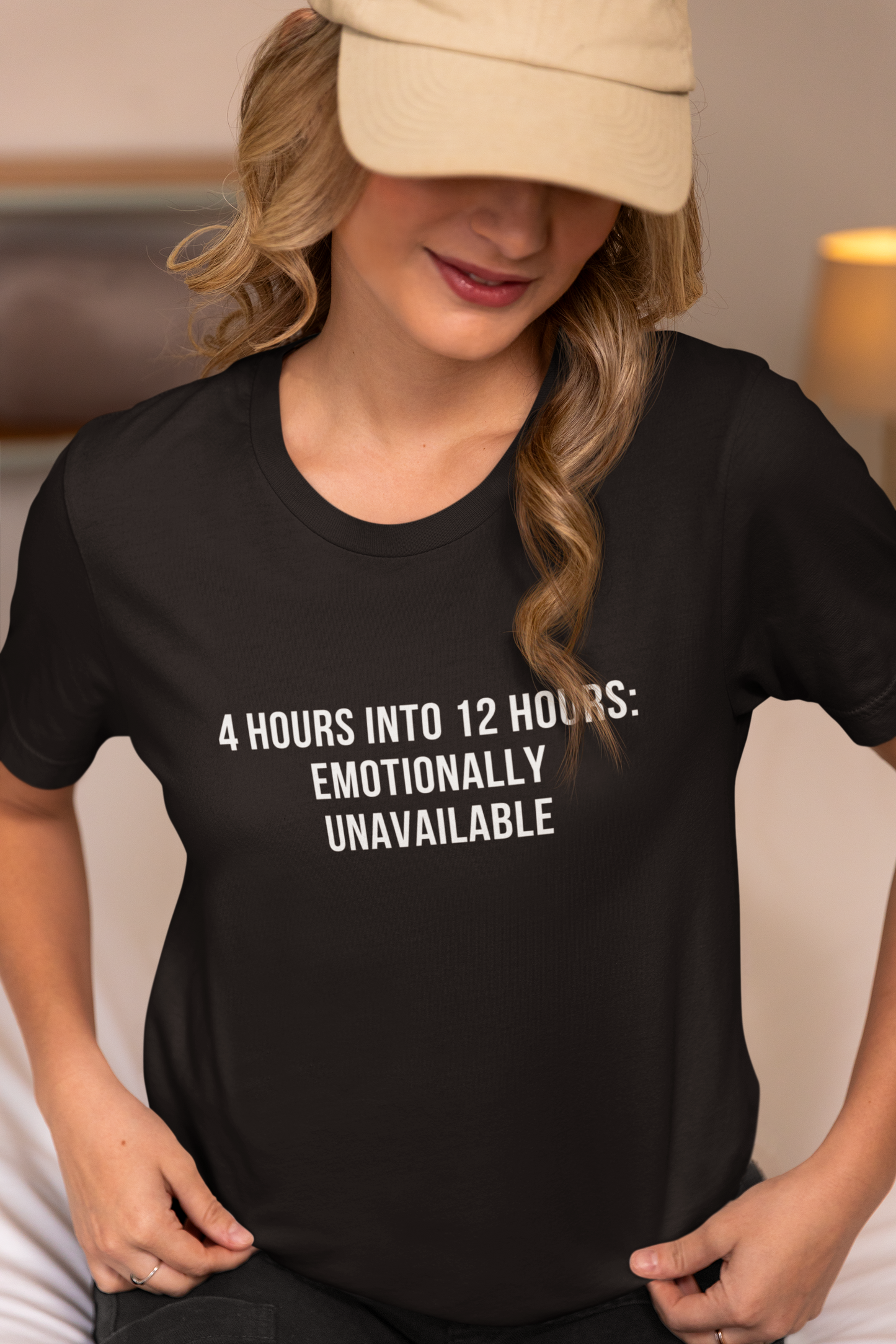 Nurse adjusting baseball cap while wearing “Emotionally Unavailable” burnout tee.