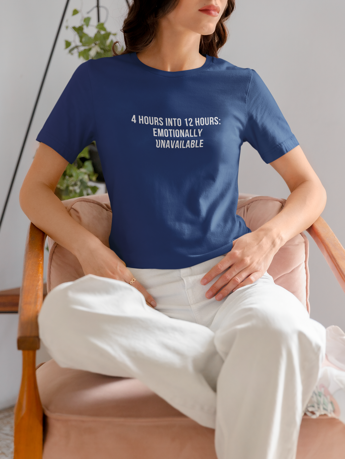Nurse sitting casually in white joggers and “Emotionally Unavailable” tee, sipping burnout relief.