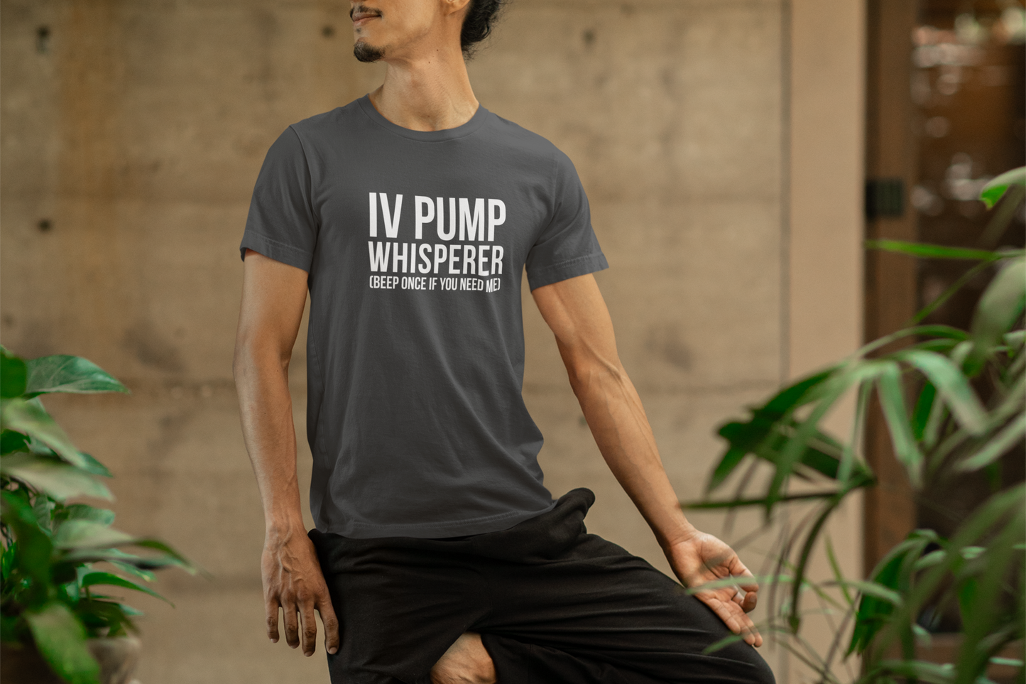 Male nurse relaxing outside while wearing the “IV Pump Whisperer” tee in navy.