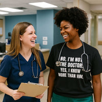 Two nurses in scrubs laughing, both wearing "No, I’m Not The Doctor. Yes, I Know More Than Him." shirts, hospital hallway.