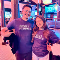 Funny nurse shirt with bold “Patients: 5, Pee Breaks: 0” design, worn by two nurses enjoying a night out