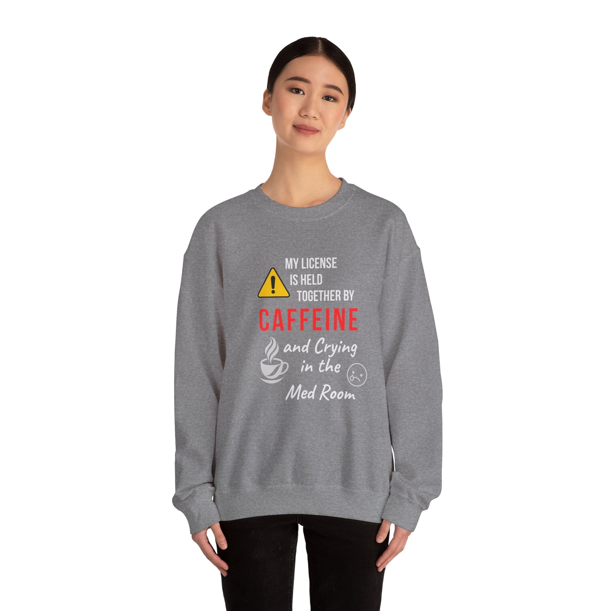 Funny nurse sweatshirt with quote “Held Together by Caffeine and Crying,” worn by exhausted RN mid-shift meltdown in breakroom
