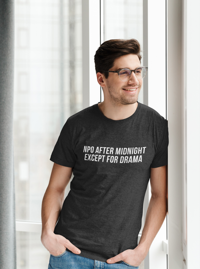 Smiling nurse in hallway wearing black shirt with quote “NPO AFTER MIDNIGHT, EXCEPT FOR DRAMA.”

