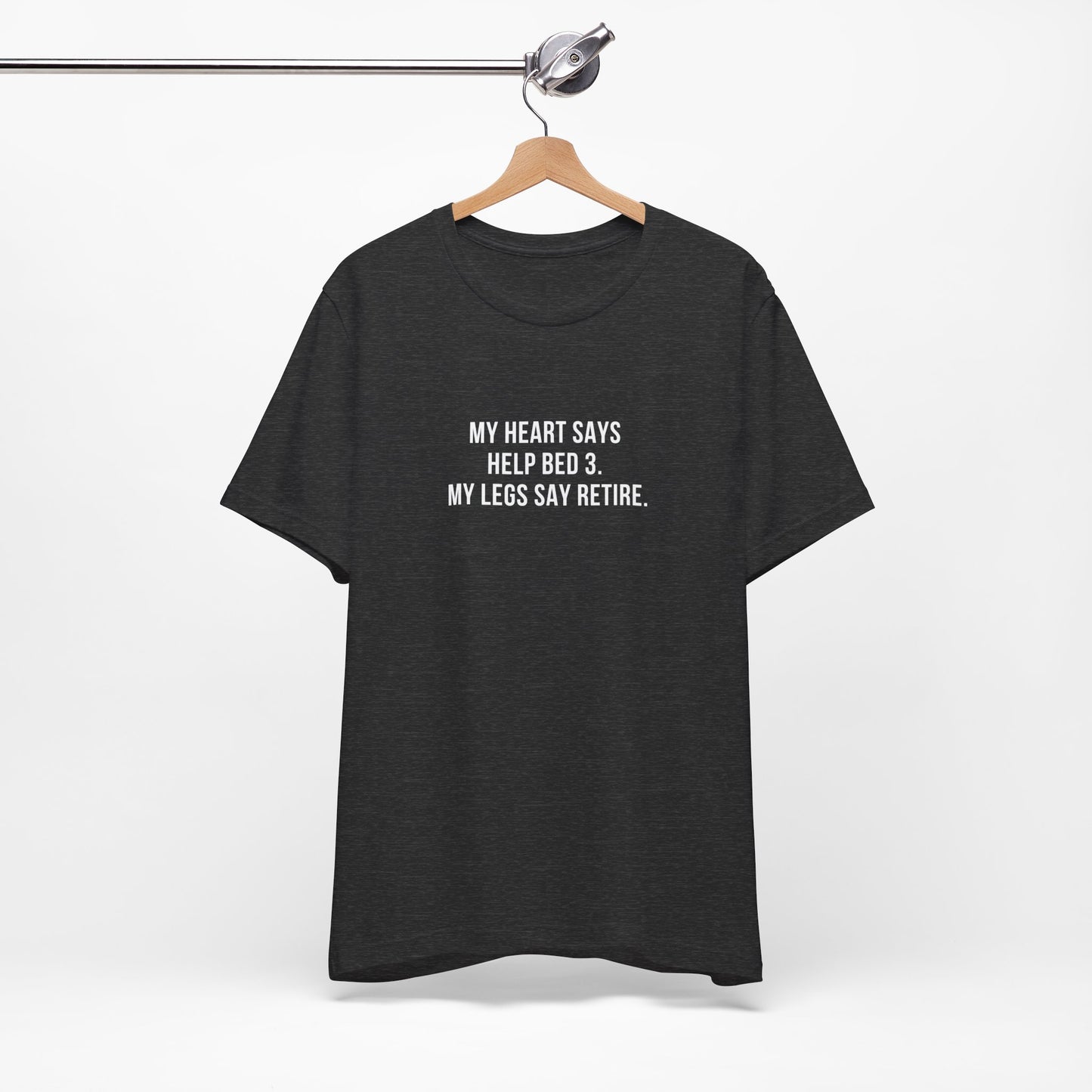 Black nurse burnout tee laid flat featuring the quote “My heart says help Bed 3, but my legs say retire.”
