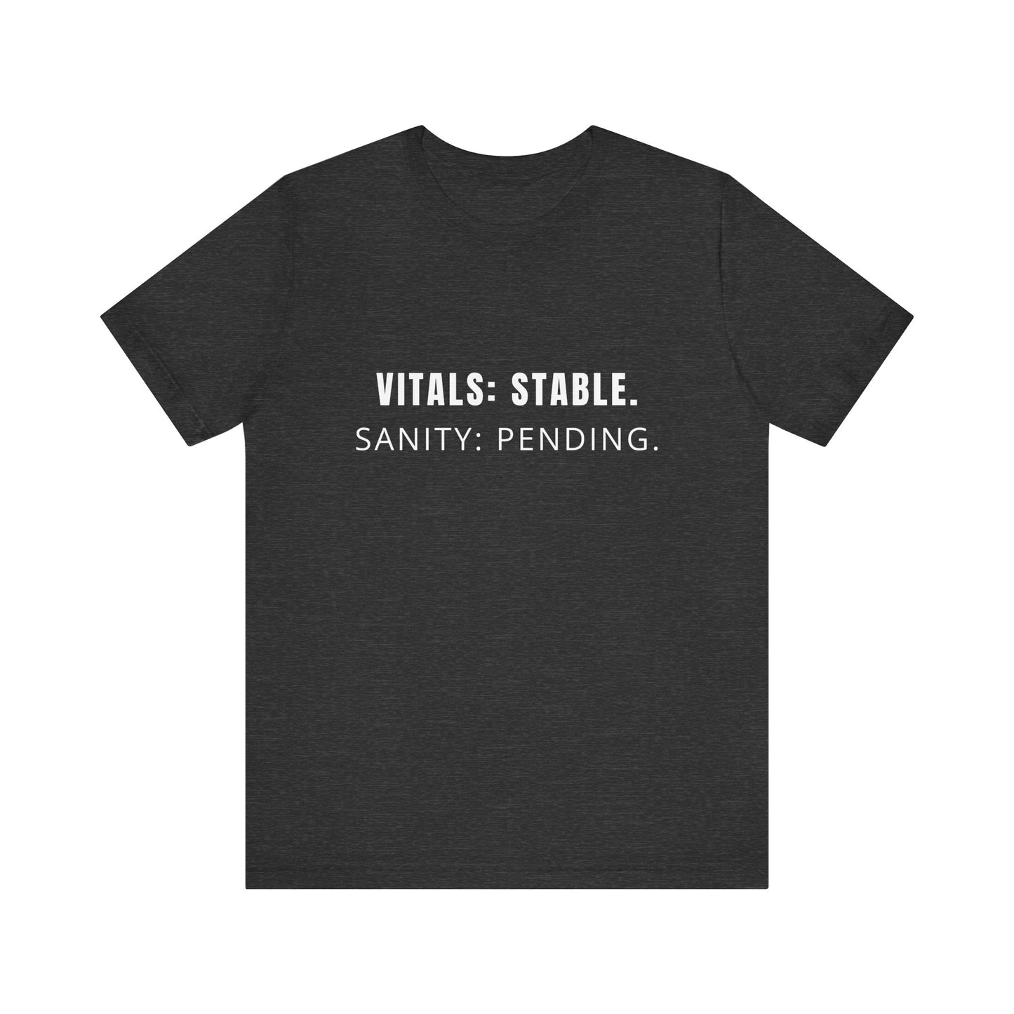 Flatlay of charcoal “Vitals: Stable. Sanity: Pending.” tee on plain background.
